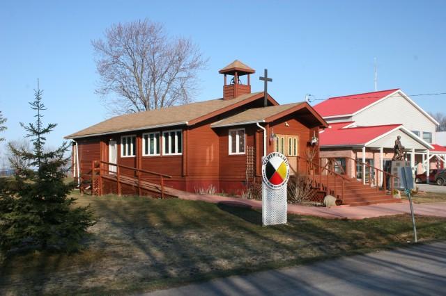 Small wooden church with a bell tower under a clear blue sky.