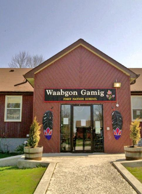Front view of Waabgon Gamig school with black and red feathers framing the entryway.